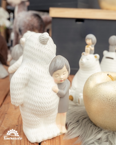 Statuette enfant et ours blanc dans un décor hivernal.